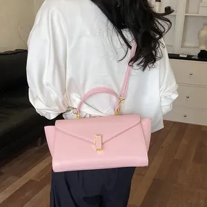Elegant pink structured crossbody handbag featuring a flap cover and gold clasp closure.