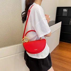 Rote halbmodförmige Satteltasche mit goldenem Ring-Detail an einem Model präsentiert