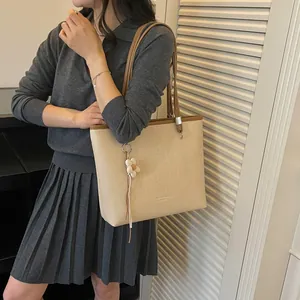 Detailed view of the large beige woven tote bag worn by a model in a lifestyle setting.
