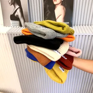 Detailed view of colorful knitted kids beanies with PPSW letter labels