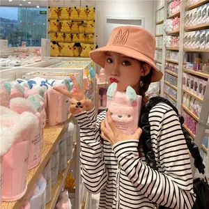 Stylish salmon pink bucket hat with cute bunny ear embroidery worn by young woman