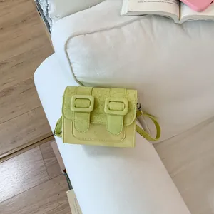 Trendy lime green square crossbody bag shown in a cozy lifestyle setting on a sofa