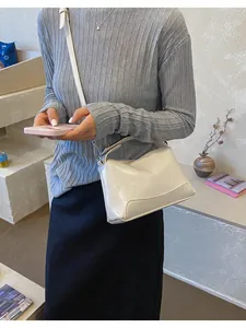 Detail van een vintage witte Boston tas gedragen door een model in een chic interieur.