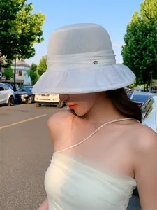 Detailed view of an elegant white breathable sun hat worn by a model in outdoor sunlight
