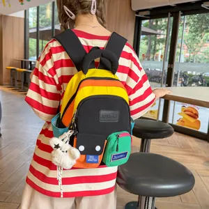 Trendy vibrant multi-colored student backpack shown being worn by a model in a cafe