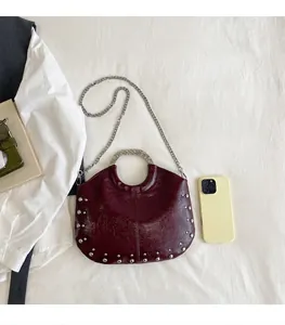 Detailed view of burgundy studded handbag with silver ring handle and chain strap