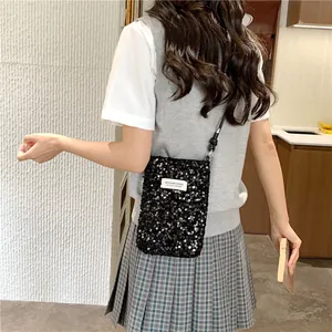 Vista dettagliata di una mini borsa a tracolla con paillettes nere indossata da una modella.