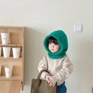 Detailed view of a green knitted hood scarf worn by a toddler in a cream-colored room