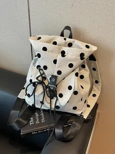 Chic beige canvas backpack featuring large black polka dots and a bunny ear flap design