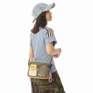 Casual olive green mini crossbody bag with clear pocket shown on model's side view