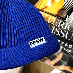 Close-up of blue ribbed knit beanie for kids with a white PPSW letter patch detail.