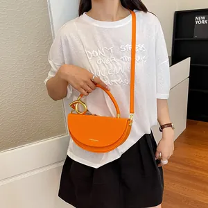 Detailansicht einer leuchtend orangefarbenen Satteltasche in Halbmondform am Model
