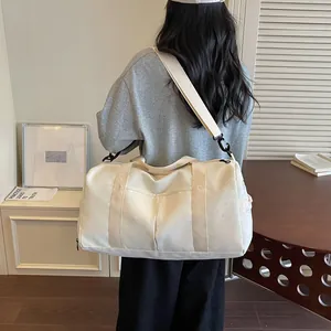 Vista detallada de la bolsa de viaje grande de color crema con patrón de estrellas en la modelo