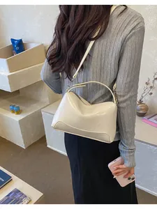 Stijlvolle crème retro Boston handtas over de schouder gedragen in een minimalistische setting.