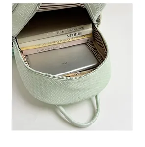 Interior detail of mint green woven backpack showing large capacity with books and tablet