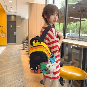 Stylish multi-color casual student backpack with charm shown on model in cafe setting