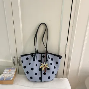 Detailed view of light blue polka dot tote bag with a palm tree charm accessory.