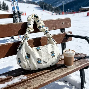Stylish white textured hobo bag with bear embroidery displayed on a snowy park bench