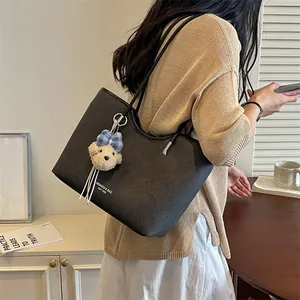 Detailed shot of a stylish black casual tote bag with a cute bear keychain charm