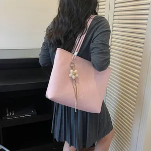 Lifestyle detail of a large pink tote bag with a flower charm worn by a female model
