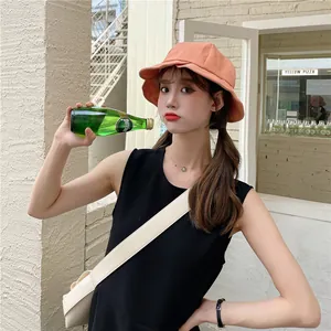 Young woman wearing an orange ruffled wide-brim sun bucket hat in a cafe setting