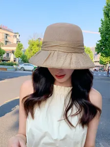 Elegant beige breathable sun hat for women with pleated brim detail in outdoor scene.