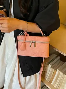 Elegant small pink suede box bag featuring a crossbody strap and top handle design.