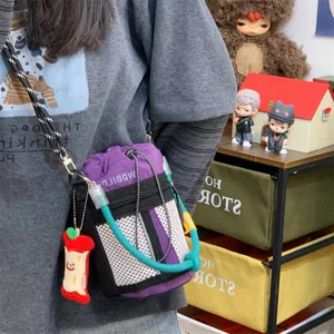 Purple bucket bag with teal rope accent and mesh pocket details shown worn by a model.