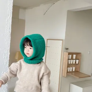 Toddler wearing a cozy green knitted balaclava hooded scarf in a minimalist home setting