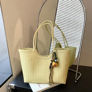 Bolso tote de tejido amarillo pálido con borla decorativa en un soporte negro