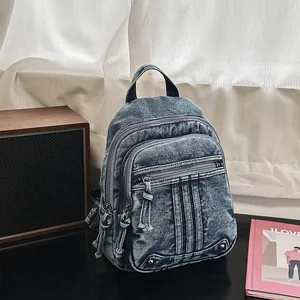 Detail of vintage washed denim backpack showing multiple functional zippers and sturdy handle