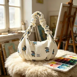 Detailed view of cream dumpling bag with cute bear embroidery and ruffled handle.