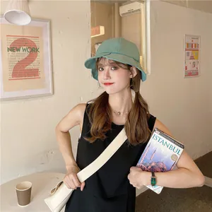 Young woman wearing a stylish green pleated bucket hat in a cozy indoor cafe setting
