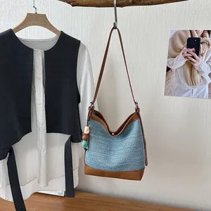 Large woven bucket bag with light blue texture and brown leather trim details for women