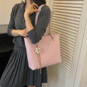 Detailed view of a pink large-capacity tote bag with a flower charm on a female model