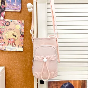 Primer plano de un bolso bandolera rosa para móvil colgado en una puerta blanca