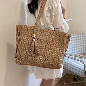 Grand sac cabas en paille tressée à la main avec pompon, porté par un mannequin