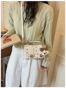 Detailed view of a white retro polka dot messenger bag featuring a cute teddy bear charm