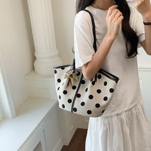 Stylish white tote bag with black polka dots shown in a lifestyle indoor setting.