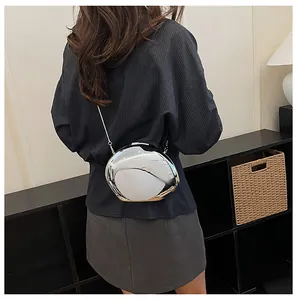 Borsa a mano a conchiglia a specchio argento con tracolla a catena indossata.