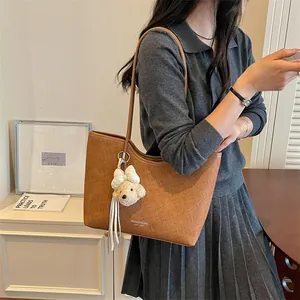 Stylish minimalist brown large capacity tote bag with bear charm worn by a model