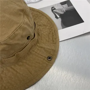 Detailopname van een kaki vintage vissershoed met denimtextuur en metalen knoop