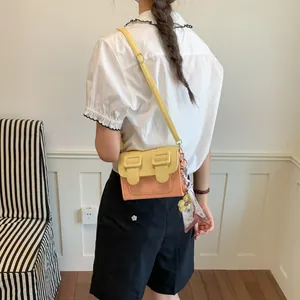 Stylish color-block crossbody square bag with a decorative floral scarf shown on a model