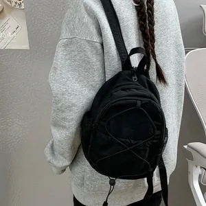 Detalle de una mini mochila negra informal con diseño de cordón elástico llevada por una modelo