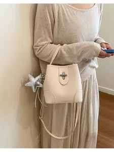 Vue détaillée d'un sac seau en cuir crème avec un accessoire breloque étoile argentée.