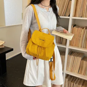 Mini sac à dos léger en nylon jaune pour femme, montré dans une bibliothèque élégante