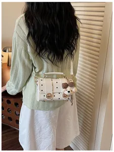 Back view of a white polka dot crossbody bag with a cute bear charm accessory