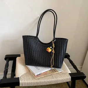 Primer plano de bolso tote tejido negro con detalle de borla elegante