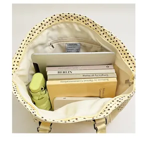 Detalle interior del bolso tote grande de lunares con portátil y libros.