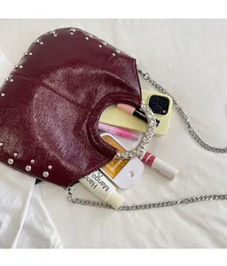 Detail shot of burgundy rivet handbag showing spacious interior with everyday essentials